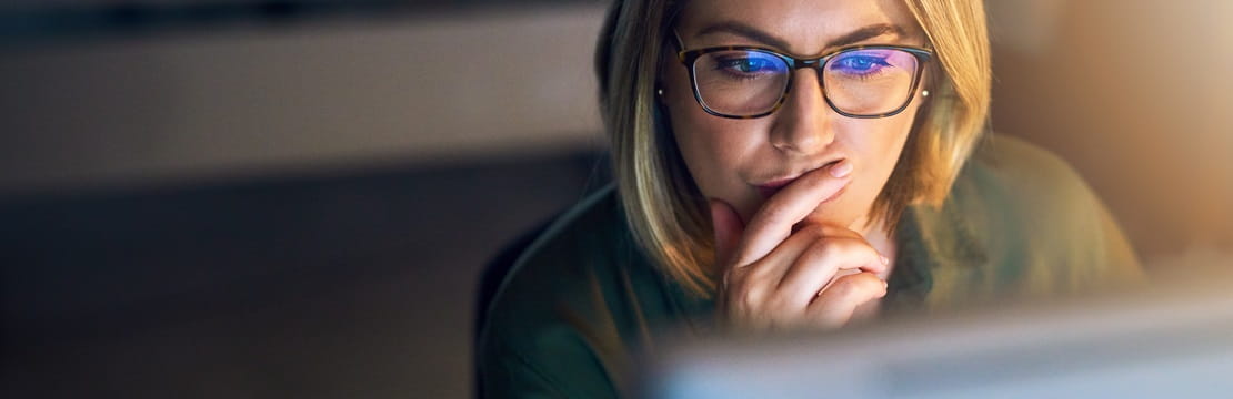 Woman wearing glasses focusing on a computer screen.